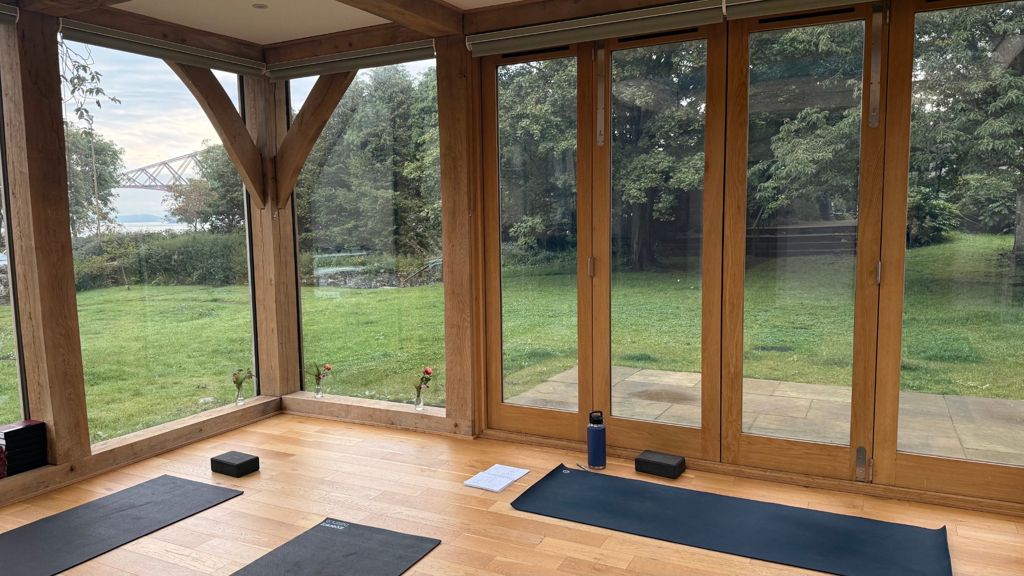 Glass walled studio with deciduous trees, Firth of Forth and Forth Rail Bridge in the background